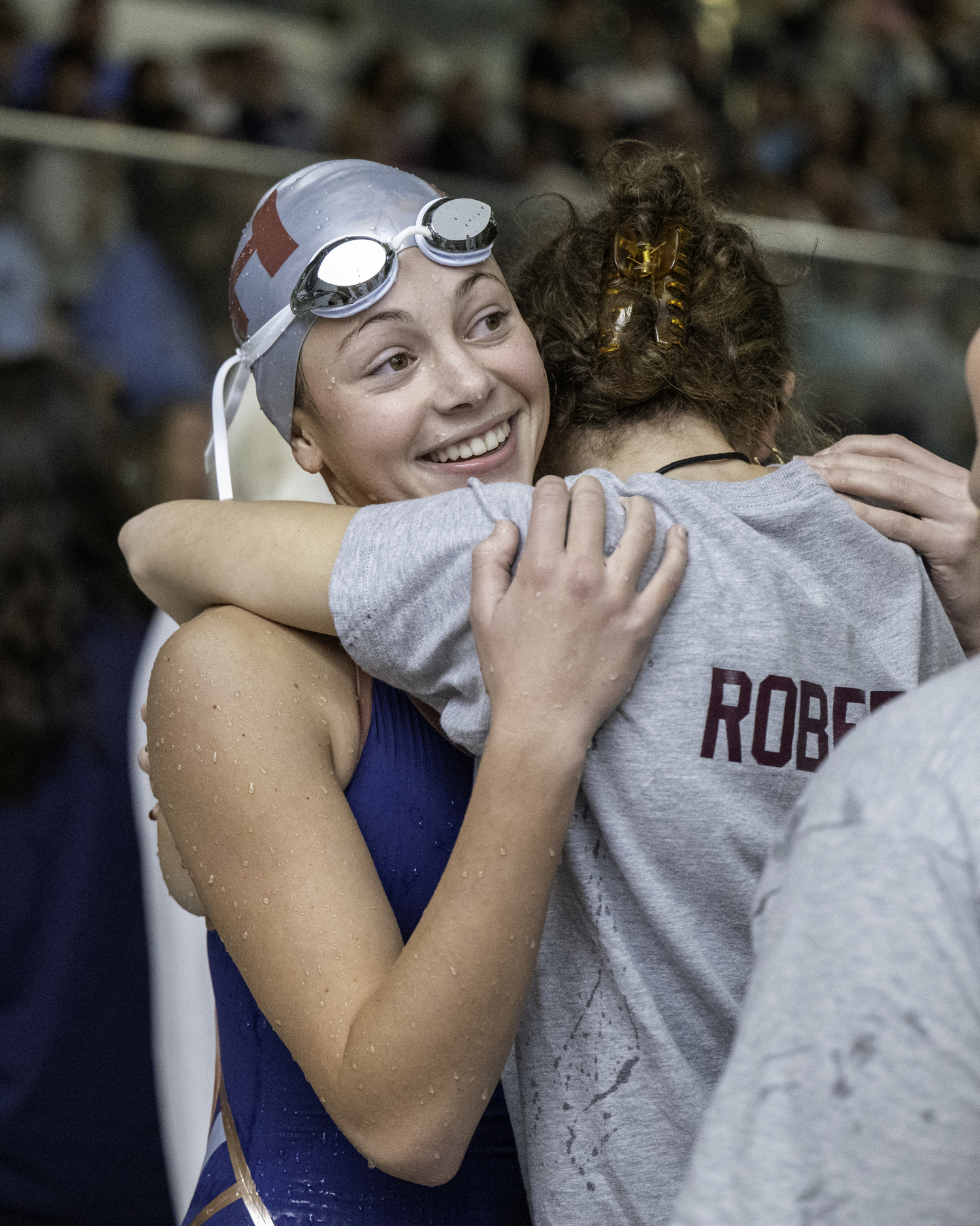 Avienne O'Shea gets a hug from teammate Olivia Robertson after her 200-yard freestyle.  MARIANNE BARNETT
