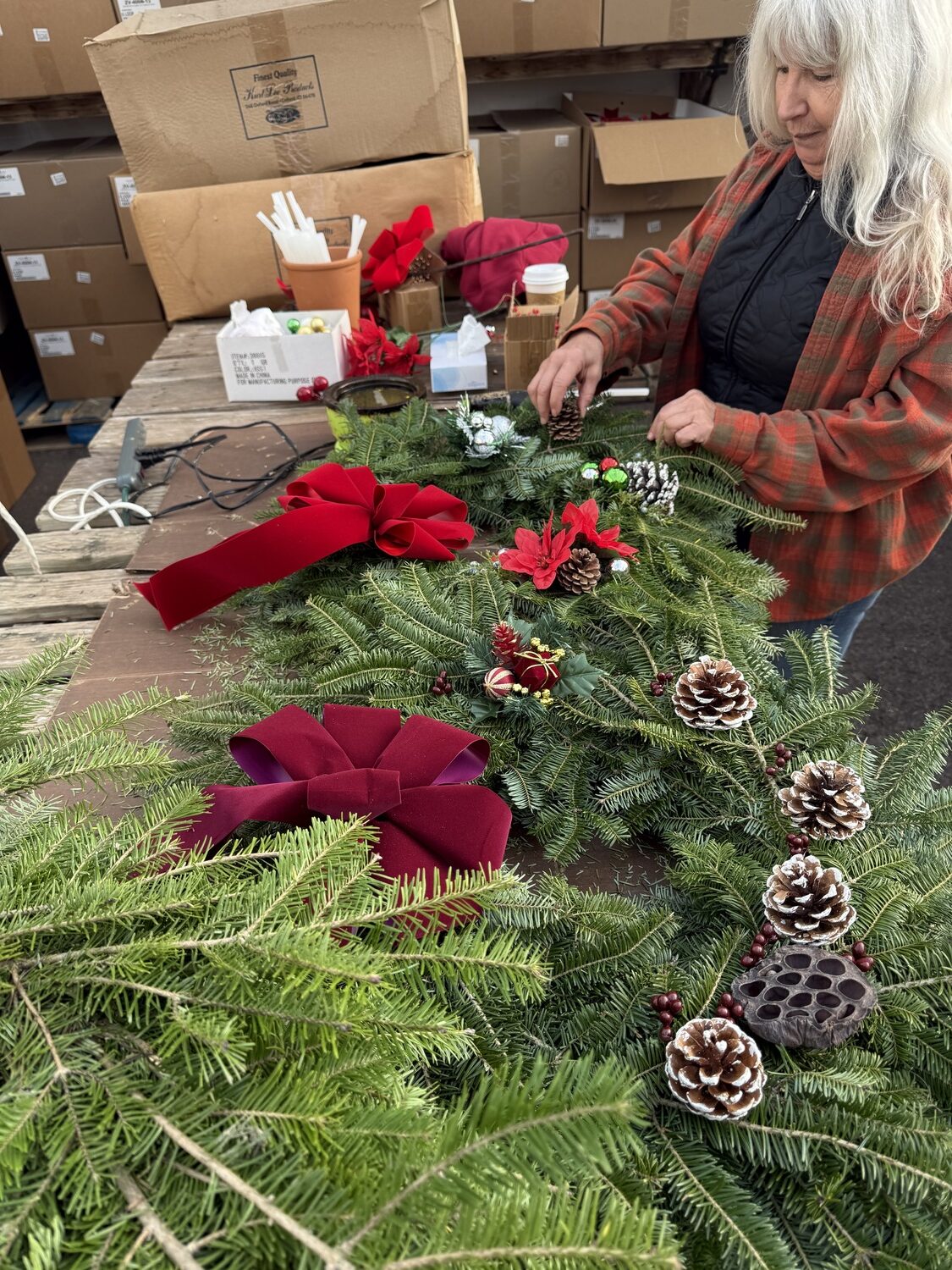 In a local garden center, an employee decorates holiday wreaths that were constructed a few hours earlier. Indoors, they dry out quickly, so they are best used as outdoor decorations. ANDREW MESSINGER