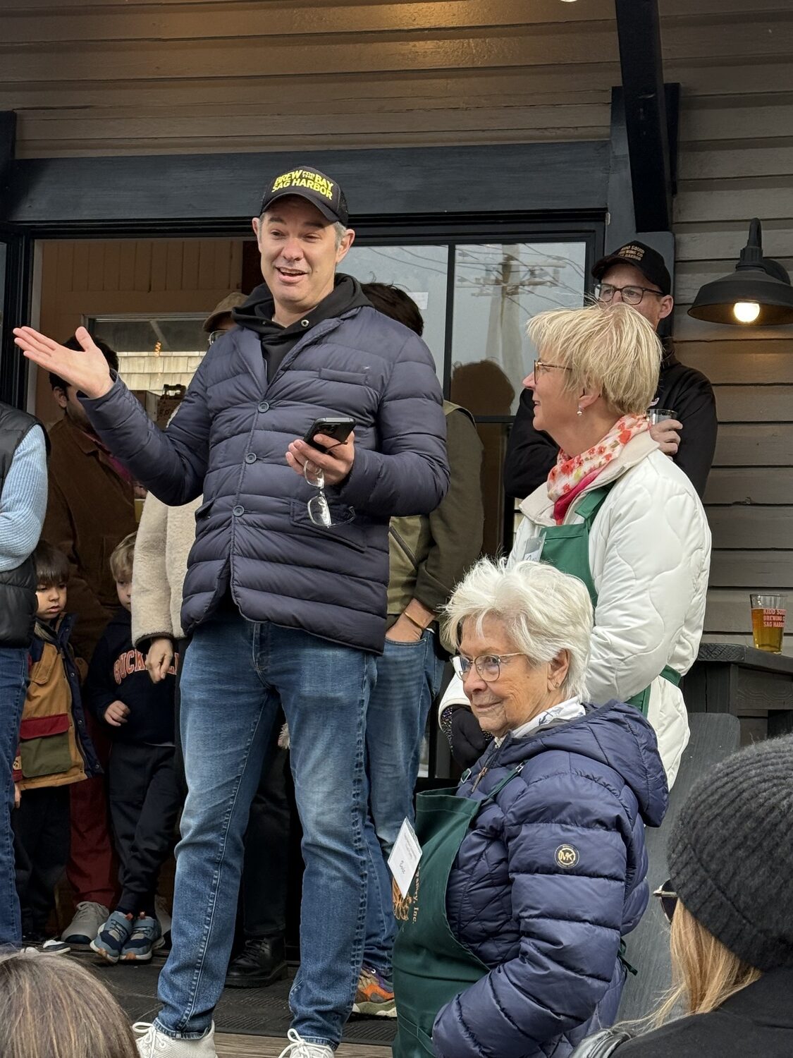 Shawn Sachs speaks to the crowd at Kidd Squid while Teri Diat and Evie Rammuno from the Sag Harbor Food Pantry look on. GAVIN MENU