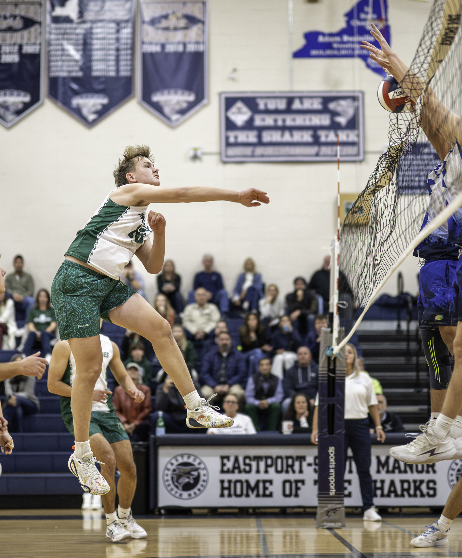 Sophomore middle hitter Luca Caumartin spikes the ball over the net during the first set. MARIANNE BARNETT