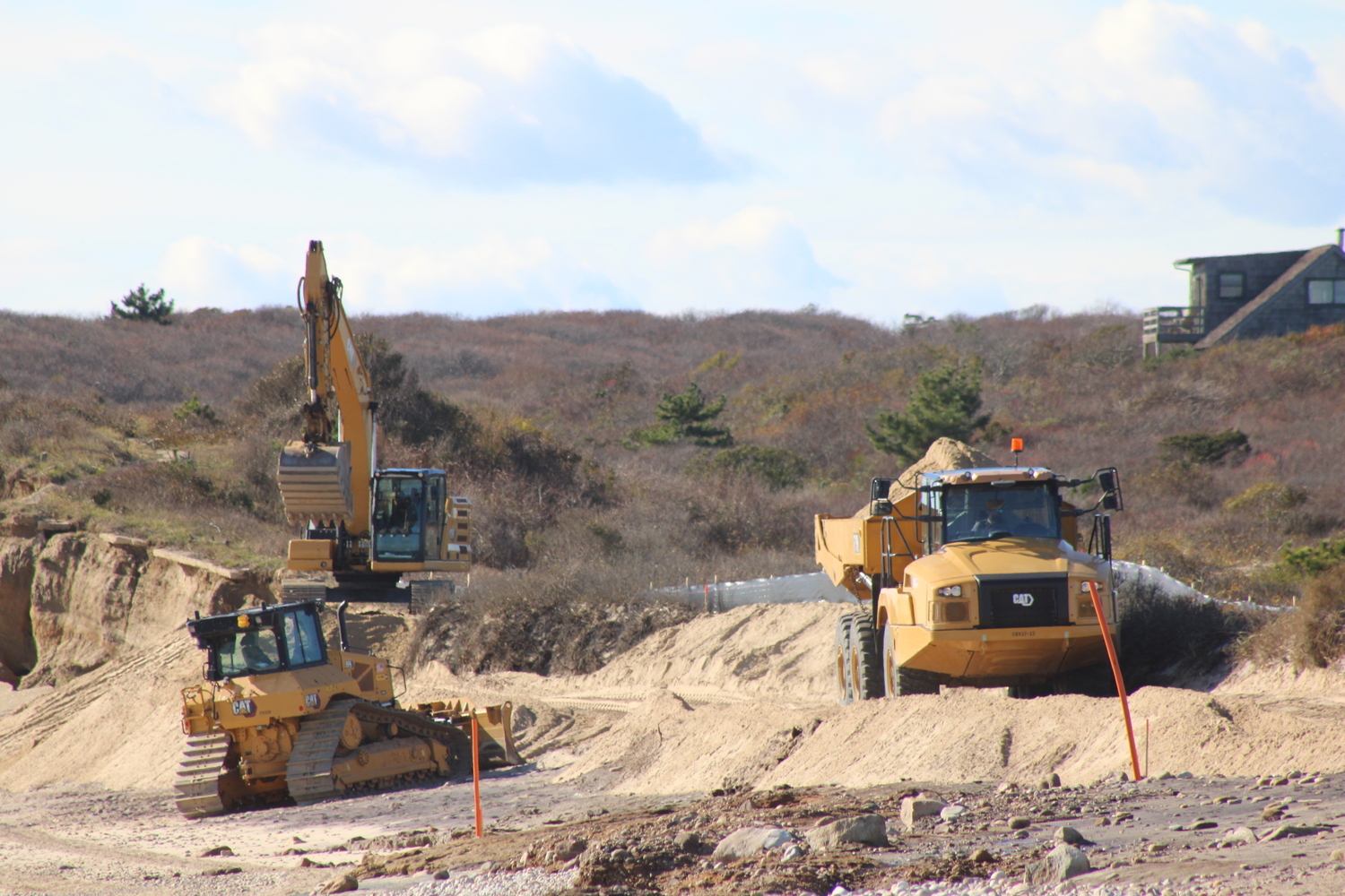 The excavators, left, mold the transported sand into the shape of the engineered dune. JACK MOTZ