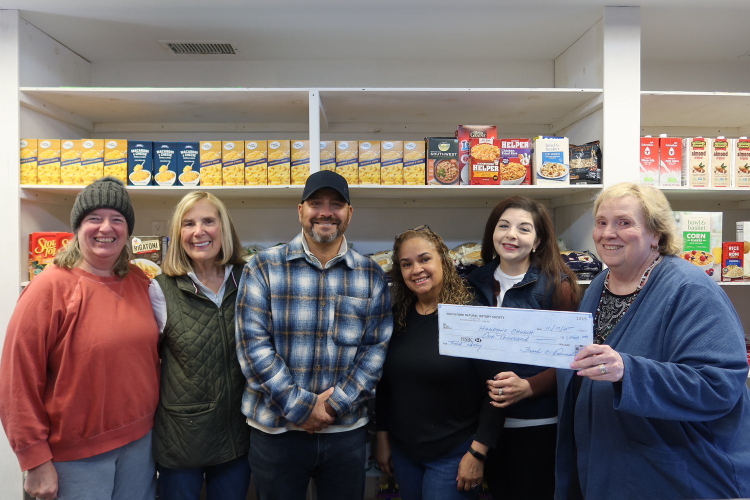 Each year, the South Fork Natural History Museum designates a portion of the proceeds from its Summer Gala to support food pantries serving underserved families on the East End, including the Hamptons Church Food Pantry in Wainscott. SOFO Executive Director Frank Quevedo, third from the left, presents a check to Dorothy Cronley, director of the Hamptons Church Food Pantry, right, while volunteers look on. COURTESY SOUTH FORK NATURAL HISTORY MUSEUM
