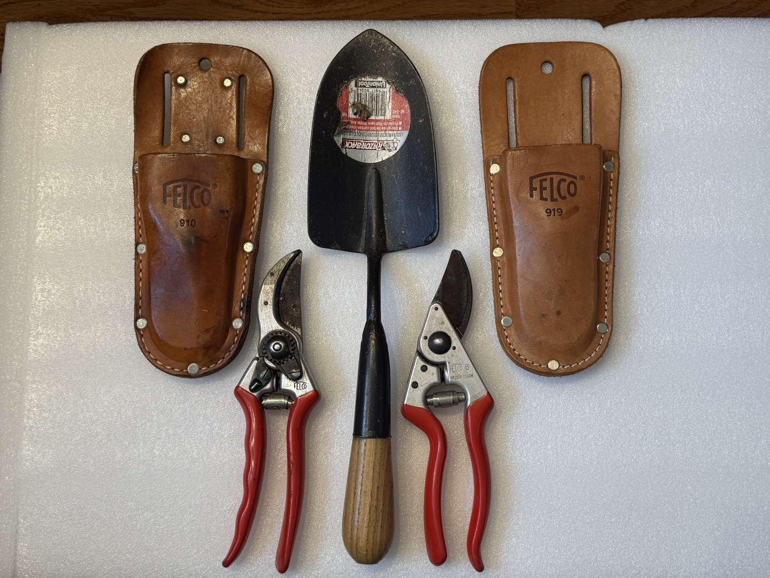 On the far top left, a Felco #910 pruner holster with belt loops and a metal belt hook on the back. On the far right, a Felco #919 holster with just the belt loop. On the bottom left, a classic Felco #2 pruner and, to the right, a Felco #8. In the center is a steel garden trowel with a wooden handle. Any or all of these will make lasting holiday gifts for the gardener in your life. ANDREW MESSINGER
