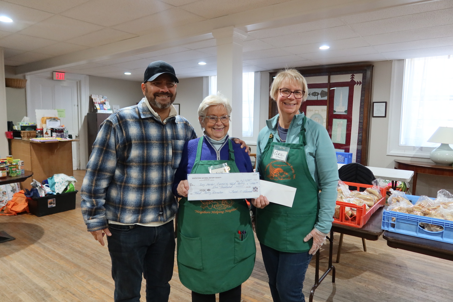Each year, the South Fork Natural History Museum designates a portion of the proceeds from its Summer Gala to support food pantries serving underserved families on the East End, including the Sag Harbor Community Food Pantry. SOFO Executive Director Frank Quevedo,  left, presents a check to pantry director Evelyn Ramunno and volunteer Terie Diat, right. COURTESY SOUTH FORK NATURAL HISTORY MUSEUM